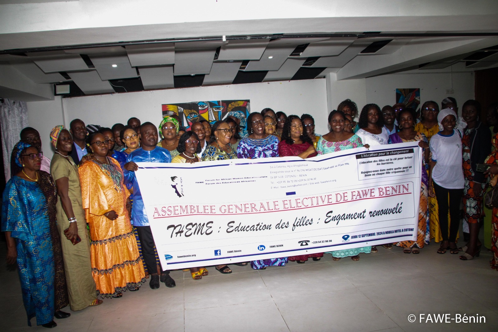Groupe de femmes tenant une grande banderole sur le thème de l’éducation des filles dans une salle intérieure