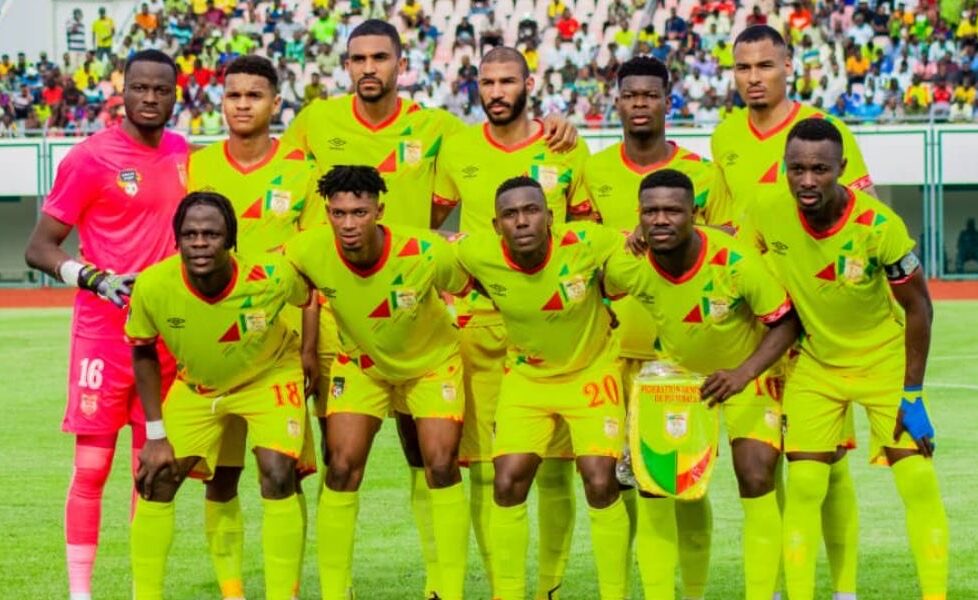 Onze joueurs en maillots jaunes posant sur un terrain de football devant une foule dans les tribunes