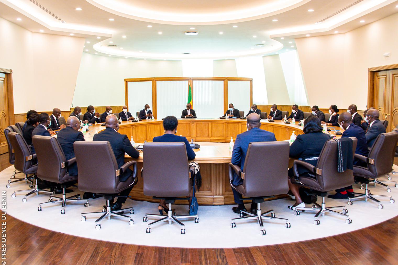 Personnes en réunion autour d’une grande table ovale dans une salle lumineuse et moderne