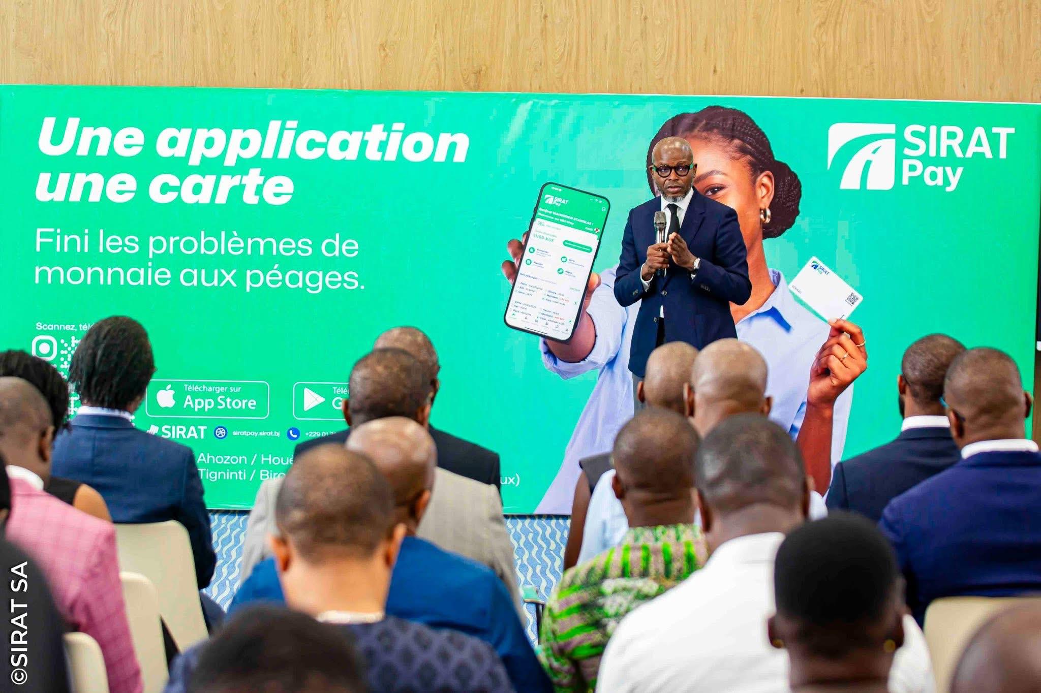 Un homme en costume présente une application mobile devant un écran vert lors d'une conférence avec un public assis de dos