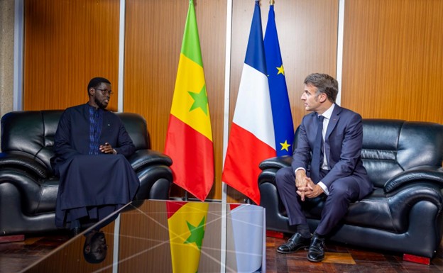 Deux hommes assis face à face dans un bureau avec les drapeaux du Sénégal et de la France entre eux