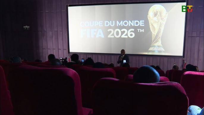 Salle de projection avec plusieurs personnes assises face à un écran affichant la Coupe du Monde FIFA 2026 et un trophée doré