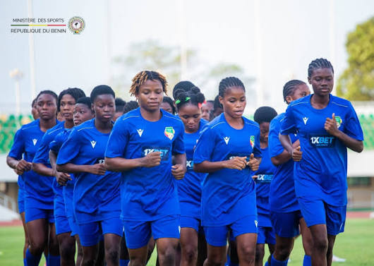 Sportives en tenue bleue courant en groupe sur un terrain herbeux lors d’un entraînement en extérieur
